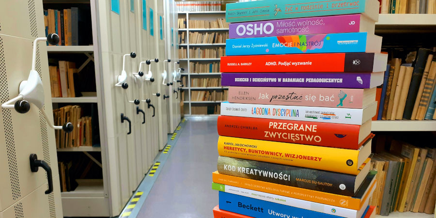 Stos różnokolorowych grzbietów książek na stole w magazynie biblioteki