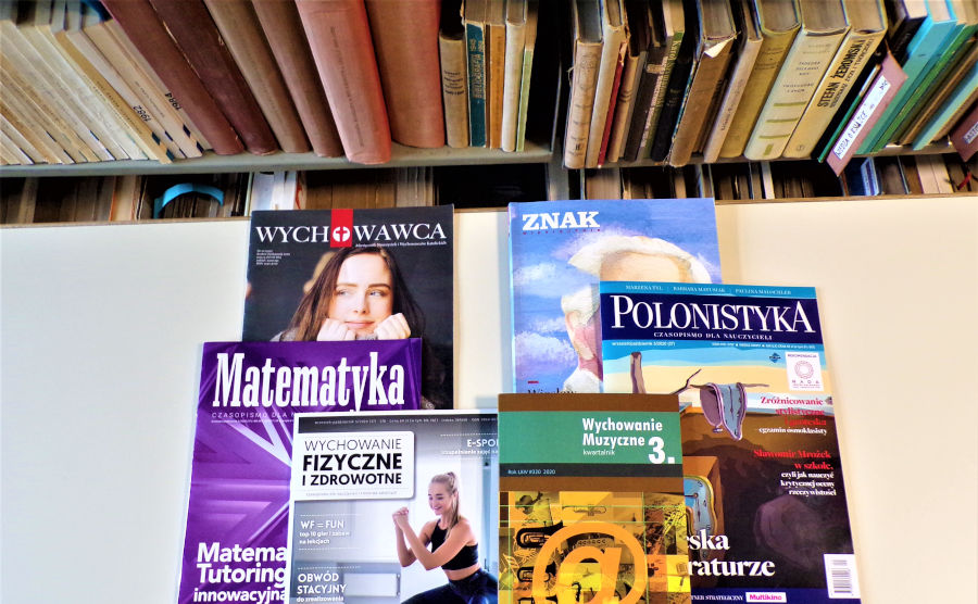 Okładki sześciu czasopism położonych na jasnym stole, w tle półka z książkami.