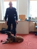 Pies policyjny waruje obok piłki i stojącego policjanta.