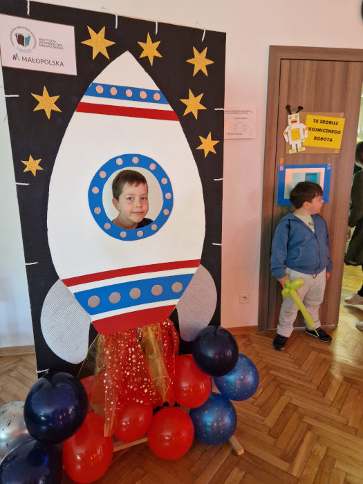 Głowa chłopca w dużej makiecie rakiety.