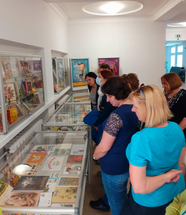 Kobiety oglądają gabloty, w których zaprezentowana jest wystawa o ilustratorach książek dla dzieci