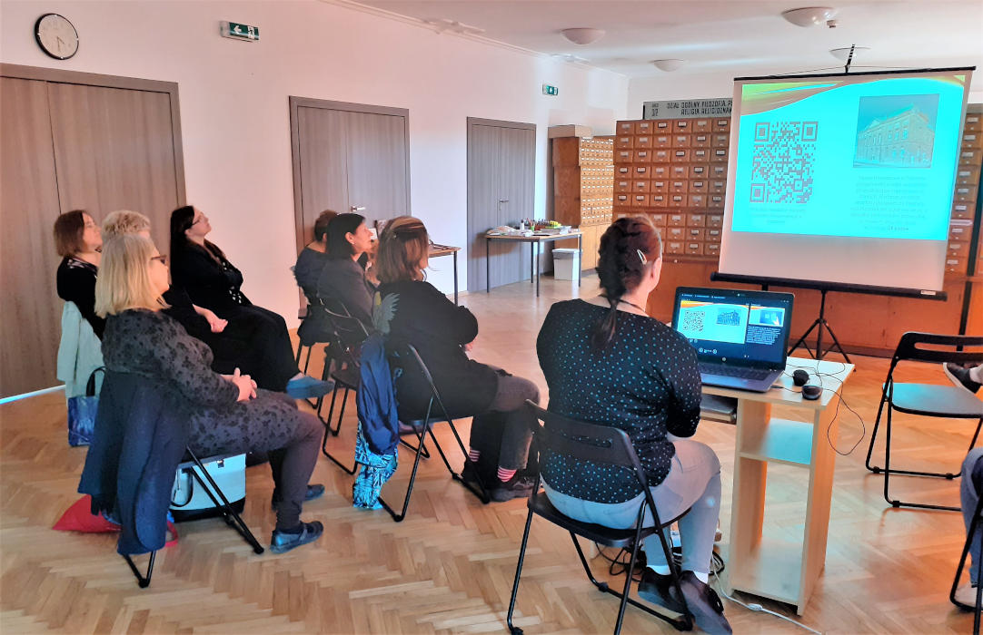 Klaudia Kierc siedzi przy laptopie i prezentuje na slajdach wykorzystanie kodów QR do celów edukacyjnych