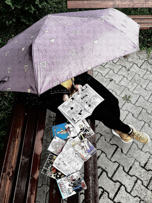 Kobieta siedząca na ławce trzymająca fioletowy parasol czyta komiks