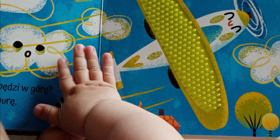 Ręka małego dziecka na książce o samolocie