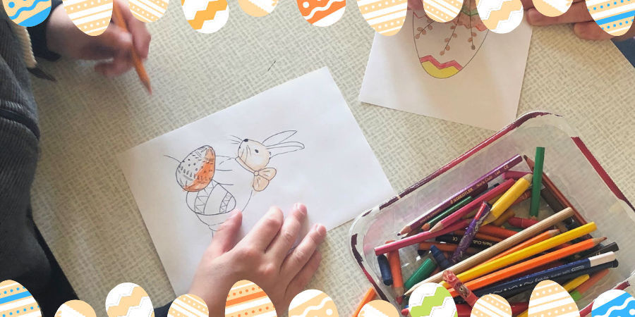 Dłonie przedszkolaka kolorują obrazek z zajączkiem i jajkami wielkanocnymi.