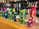 Kolorowe roboty wykonane przez uczniów na tle półek z książkami