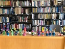 Na stole kolorowe roboty wykonane przez uczniów, w tle półki z książkami