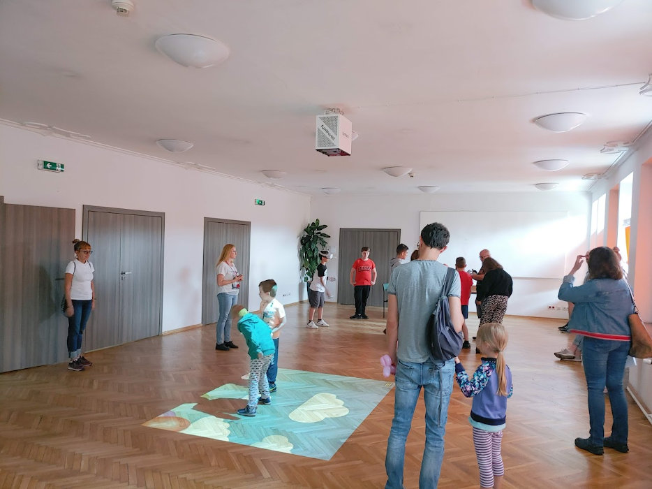 Grupa dzieci bawiących się na interaktywnej podłodze "Magiczny dywan" oraz korzystających z gogli Oculus Quest 2.