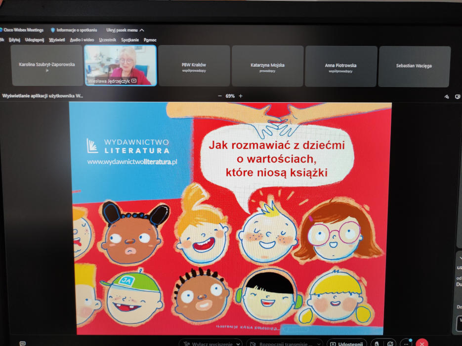 Na ekranie komputera slajd z uśmiechniętymi buziaki rysunkowych dzieci. U góry wizerunek prowadzącej Pani Wiesławy Jędrzejczyk.