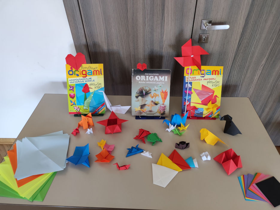 Na stoliku 3 książki o Origami, papier oraz przykładowe modele złożone metodą origami