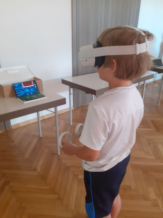Chłopiec z goglami do VR, przed Nim ustawiony tablet który pokazuje