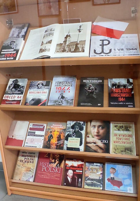 W gablocie za szkłem na półkach poukładane frontem książki o Powstaniu Warszawskim.